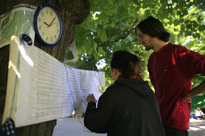 Závodnice zapisuje další ujetý okruh do velké tabulky umístěné poblíž startu.